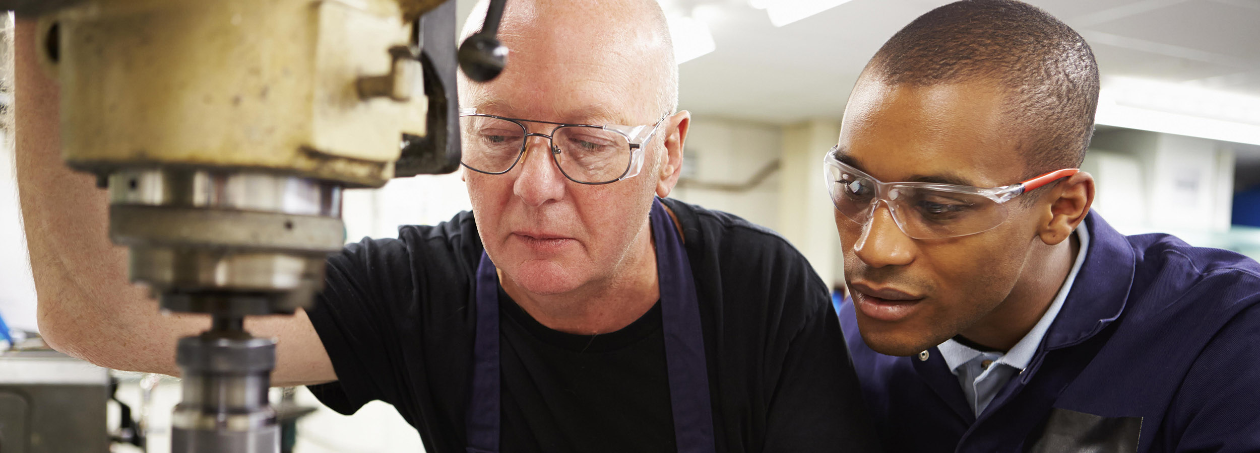 Engineer Teaching Apprentice To Use Milling Machine